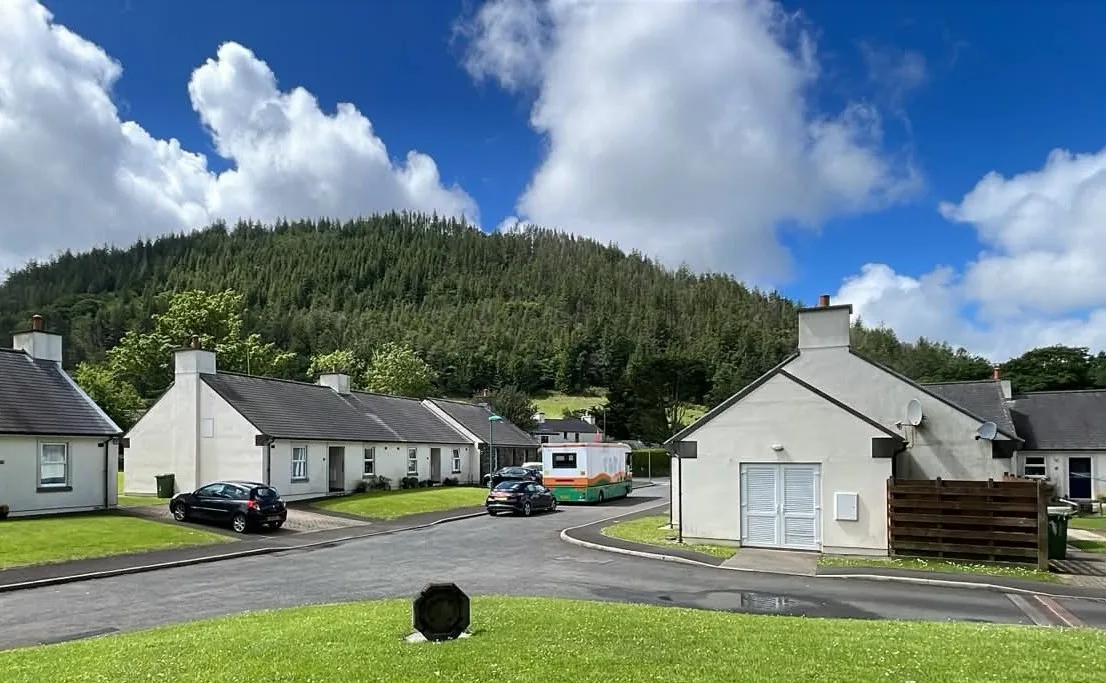 The Mobile Library parked on a village road with wooded hills behind